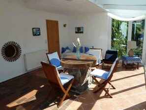 A sunlit patio with a round table, chairs, and a small table with a lamp. - Schiel apartment rental - Apartment (Zempin)