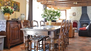 Un'accogliente sala da pranzo con tavolo e sedie in legno, un vaso con fiori e un muro in pietra con camino.