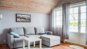 En moderne stue med en grå hjørnesofa, et hvidt sofabord og et stort vindue med lette gardiner.