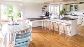Et moderne køkken med en central ø, barstole og et spisebord med stole.