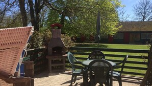 A patio area with a brick floor, a stone-built outdoor oven, and two plastic chairs. - Vacation apartment Möwe (ground floor) - Windland Ranch - Equestrian farm with vacation apartments (House (Altenkirchen)