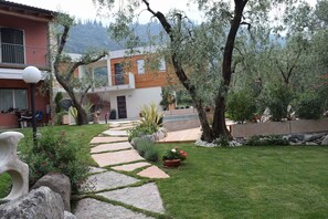 Stroll through the beautifully maintained garden, surrounded by lush greenery and vibrant flowers, to the two-story building with large windows and a balcony.