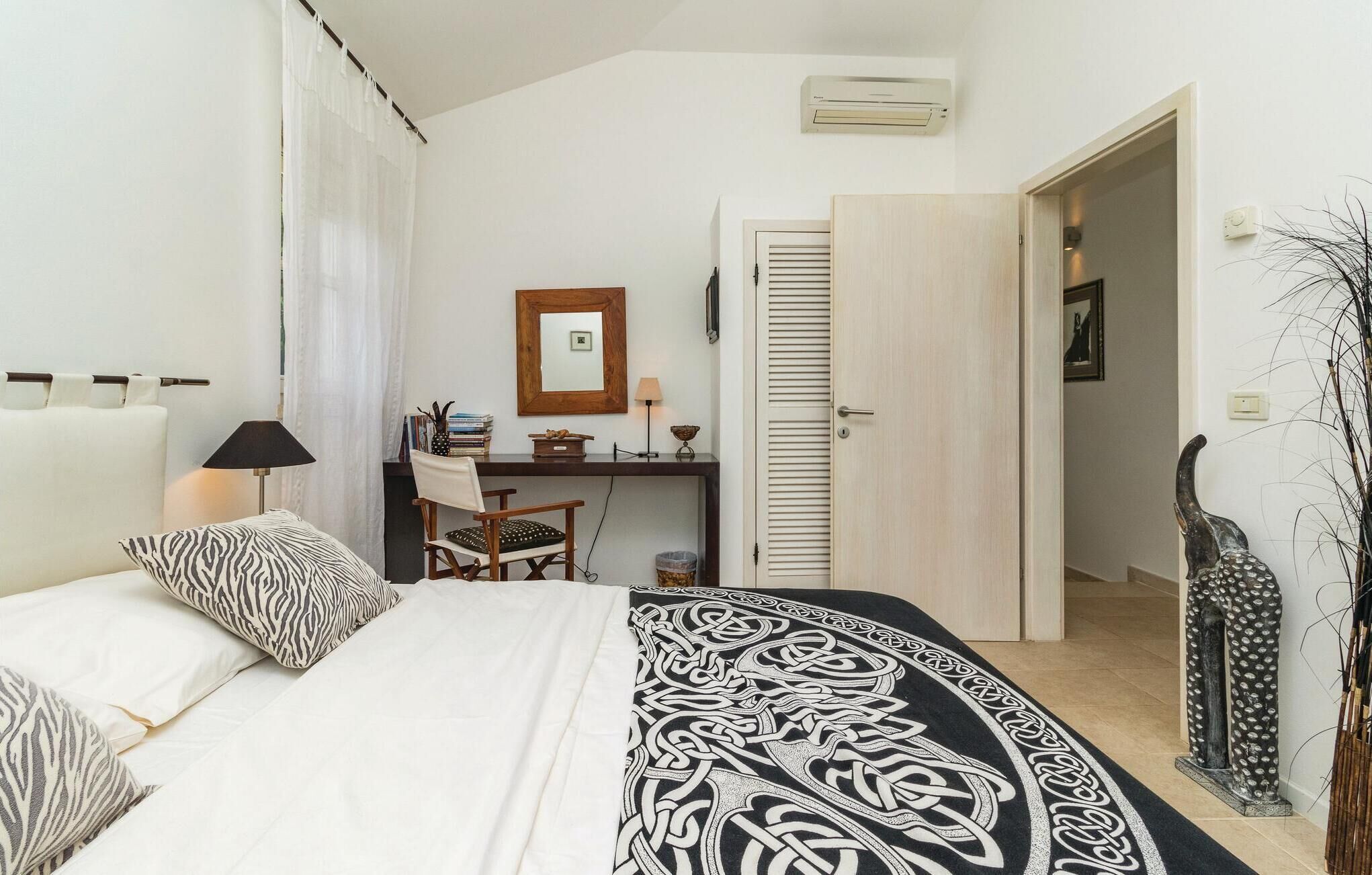 Un dormitorio con cama, escritorio, silla y armario.