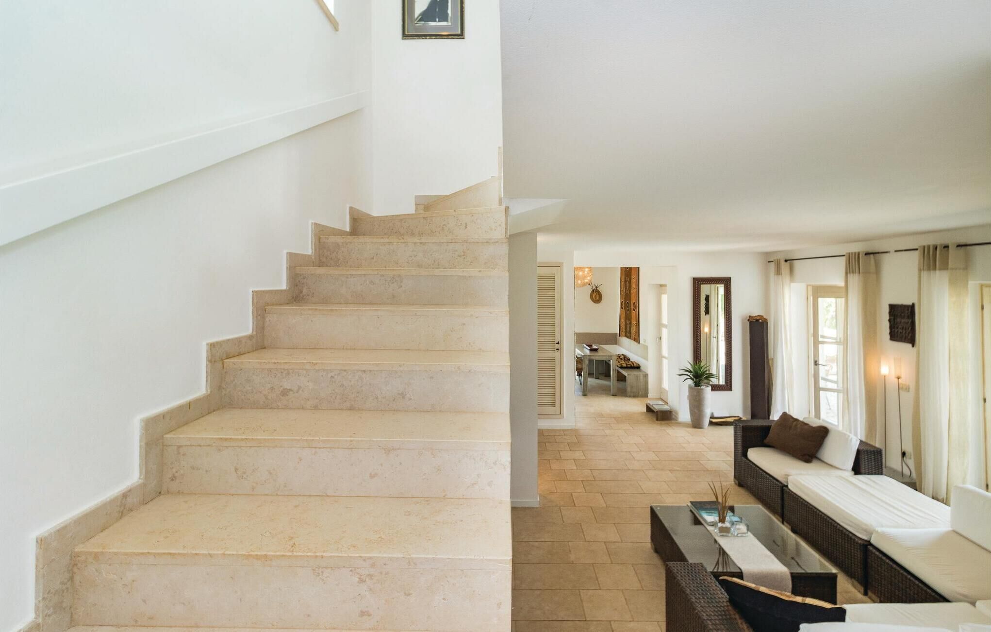 A staircase leading to a dining area with a sofa and a mirror.