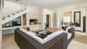A modern living room with a fireplace, wicker furniture, and a staircase.