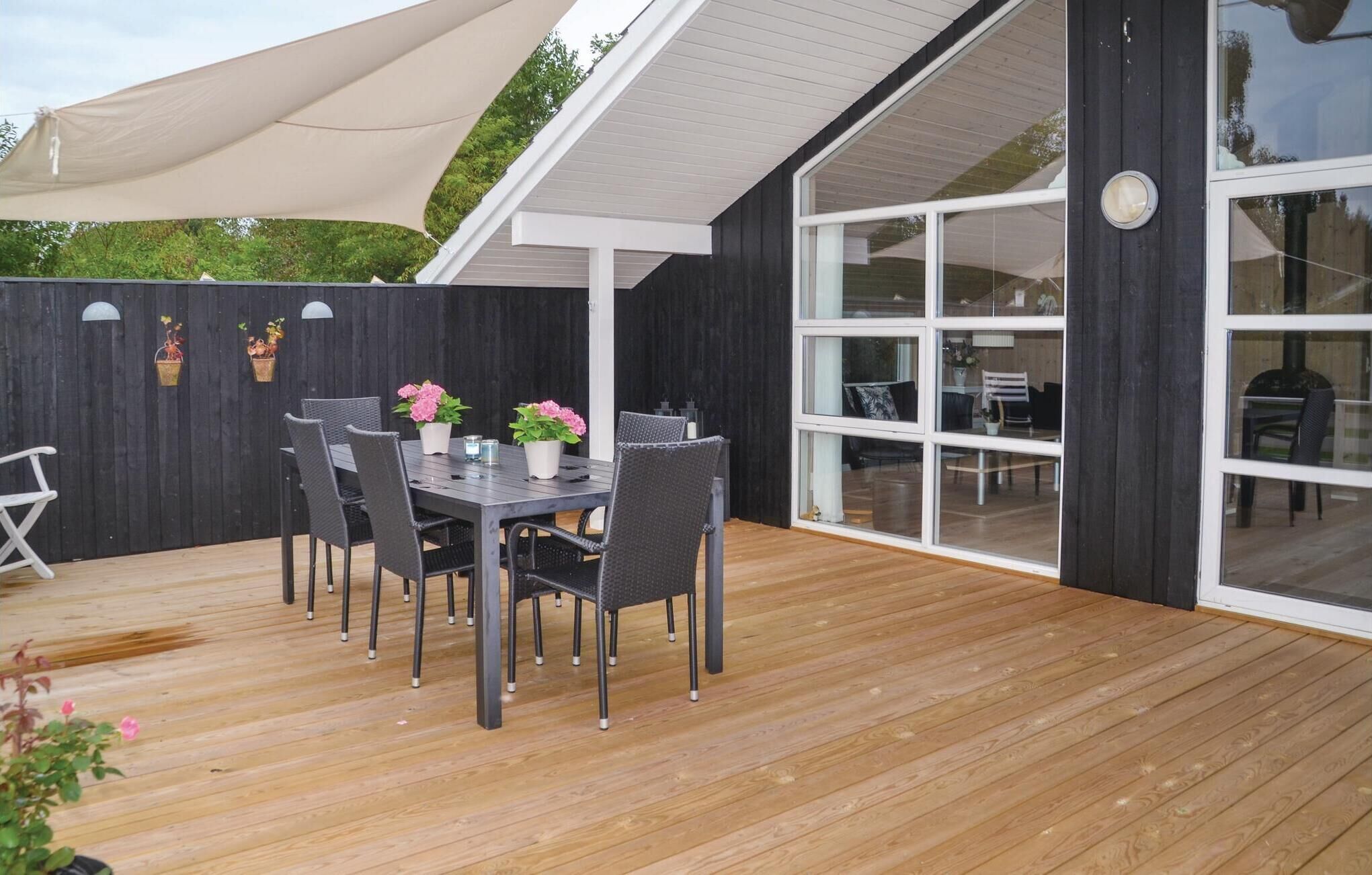 Une terrasse extérieure avec une plateforme en bois, une table et des chaises, ainsi que des plantes en pot.