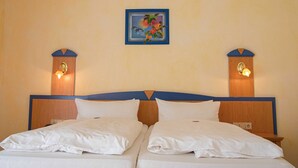 Un lit double avec deux oreillers, une tête de lit en bois et deux lampes de chevet fixées au mur.