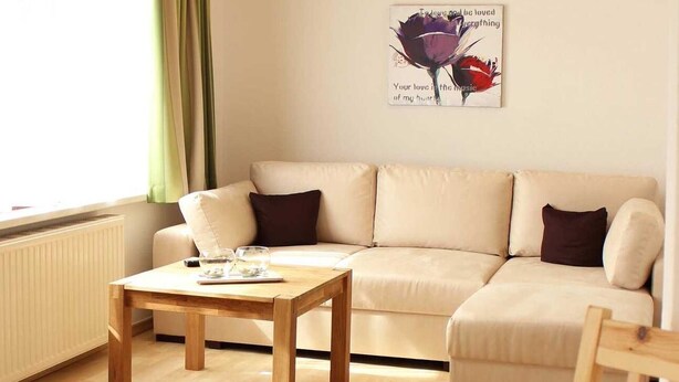 Una sala de estar acogedora con un sofá, una mesa de centro de madera y un comedor con platos, tazas y una servilleta.