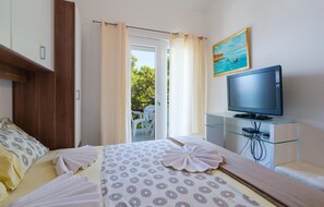 A hotel room with a bed, a TV on a glass stand, a painting on the wall, and a view of the outdoors. - Stunning home in Zastrazisce with house sea view (Zastrazisce)