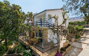A building with a white facade, a balcony with a metal railing, and a stone pathway leading to the entrance. - Stunning home in Zastrazisce with house sea view (Zastrazisce)