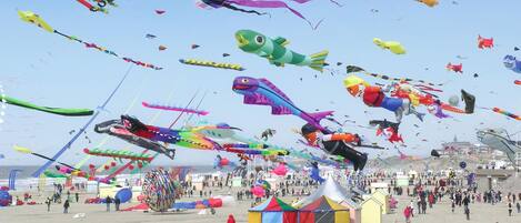 A beach with numerous colorful kites and tents.