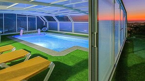 A swimming pool with a glass enclosure, green artificial grass, and lounge chairs. - Gorgeous home in Santa Susanna (Santa Susanna)