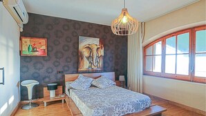 A bedroom with a bed, a chair, a lamp, a painting, and a window. - Gorgeous home in Santa Susanna (Santa Susanna)
