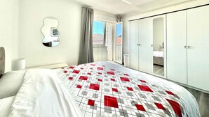 Quarto com cama, guarda-roupa, espelho e janela com cortinas.