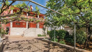 A courtyard with a stone wall, a red building, and a pergola with vines. - 1 bedroom gorgeous apartment in Rovinj (Rovinj)