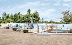 Un espace aménagé au bord de la piscine, avec des chaises longues, une table et un coin salon abrité.