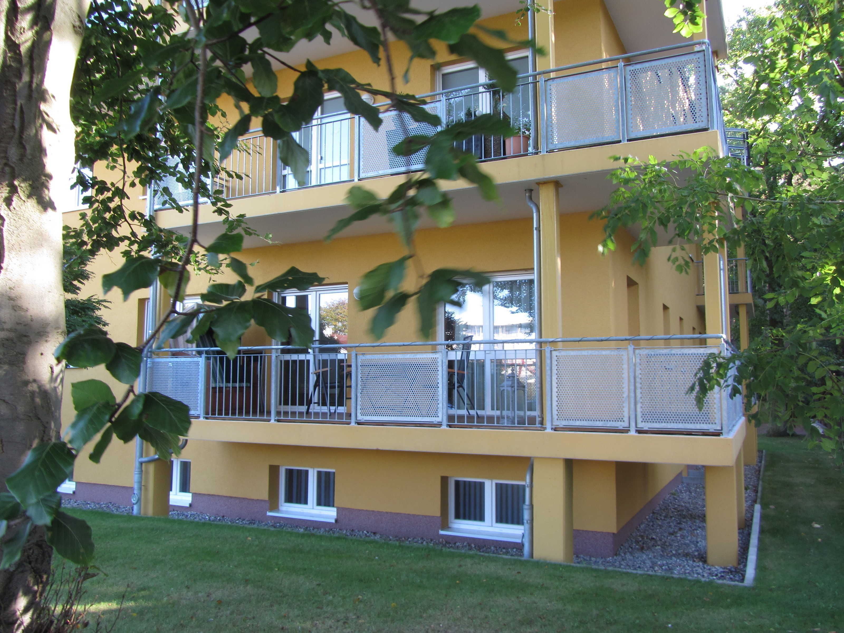 A multi-story building with balconies, a flat roof, and a small window.