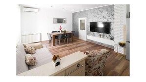 Ein modernes Wohnzimmer mit einer Couch, einem Esstisch und einem an einer Marmorwand montierten Fernseher.