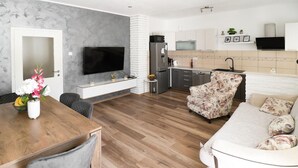A modern living room with a wooden dining table, a sofa, and a TV.