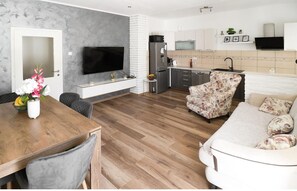 A modern living room with a wooden dining table, a sofa, and a TV.