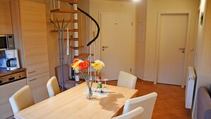 A compact kitchen with a dining table, chairs, a microwave, and a coffee machine. - Apartment with Balcony - Ferienhaus Alt-Baabe (Baabe)