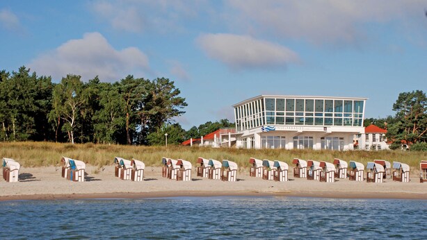 A beachside building with a modern design, a row of beach huts, and a view of the sea. - Apartment with Balcony - Ferienhaus Alt-Baabe (Baabe)