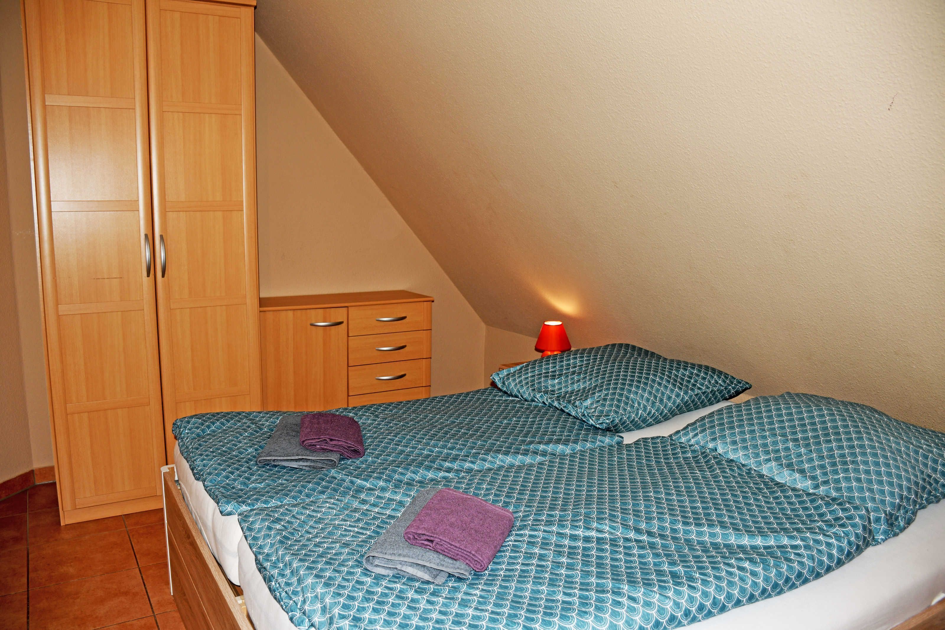 A bedroom with a bed, a wardrobe, a nightstand, and a red lamp.