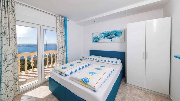 Una camera da letto con un letto, un armadio, un quadro e vista panoramica attraverso una porta vetrata.