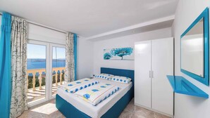 Una camera da letto con un letto, un armadio, un quadro e un balcone con tende.