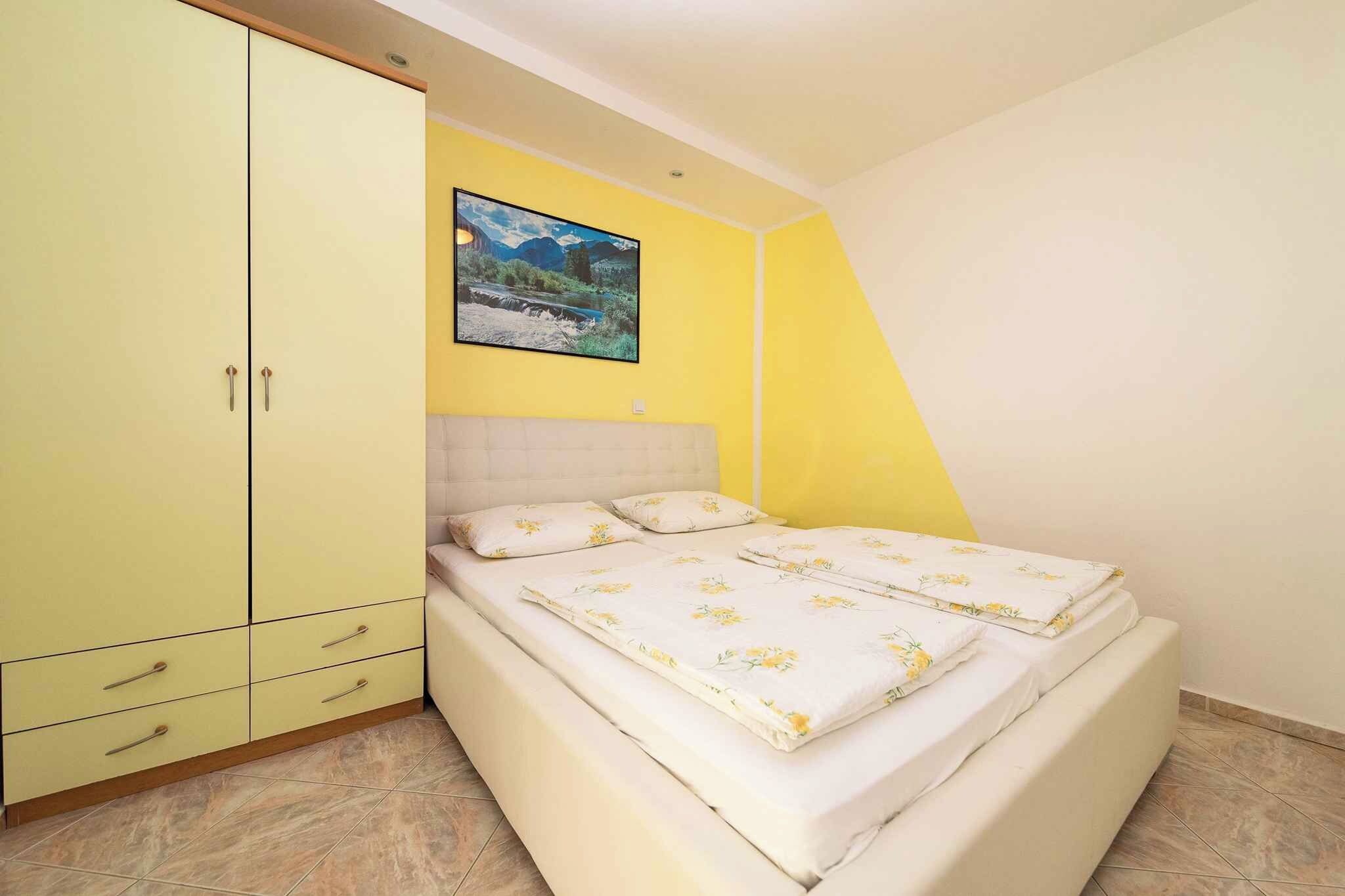 Une chambre à coucher avec un lit, une armoire, un tableau et un mur jaune.