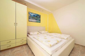 A bedroom with a bed, a wardrobe, a painting, and a yellow wall.