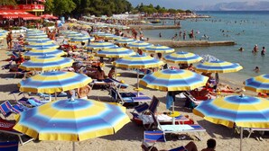 Una spiaggia con numerosi ombrelloni e lettini.