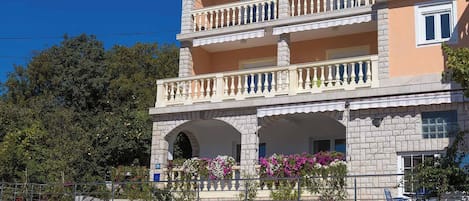 A multi-story building with balconies, a garage, and potted plants.