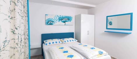Un dormitorio con cama, armario, espejo y cortina con estampado floral.