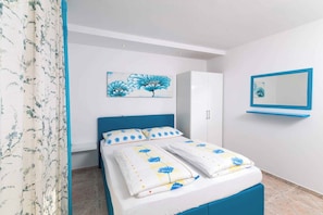 A bedroom with a bed, a wardrobe, a mirror, and a floral curtain.