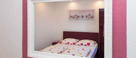 Un dormitorio con cama, mesita de noche y espejo.