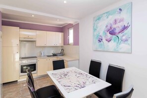 Una cocina moderna con comedor, que incluye una mesa con sillas, un cuadro en la pared y un ventanal.