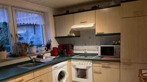 Una cocina compacta con lavadora, microondas y lavabo.