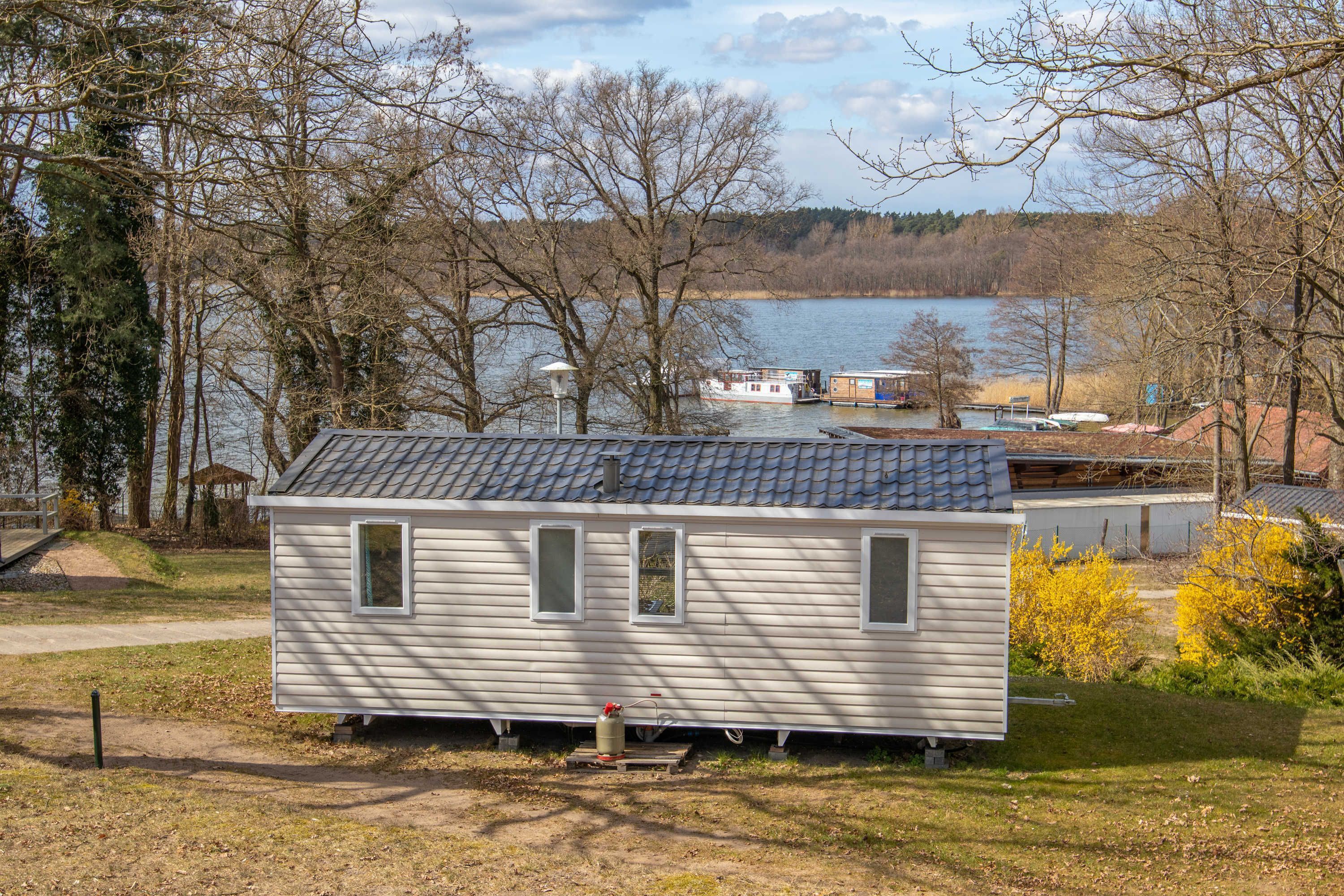 A small, single-story cabin with a sloped roof, a small porch, and a visible water heater.