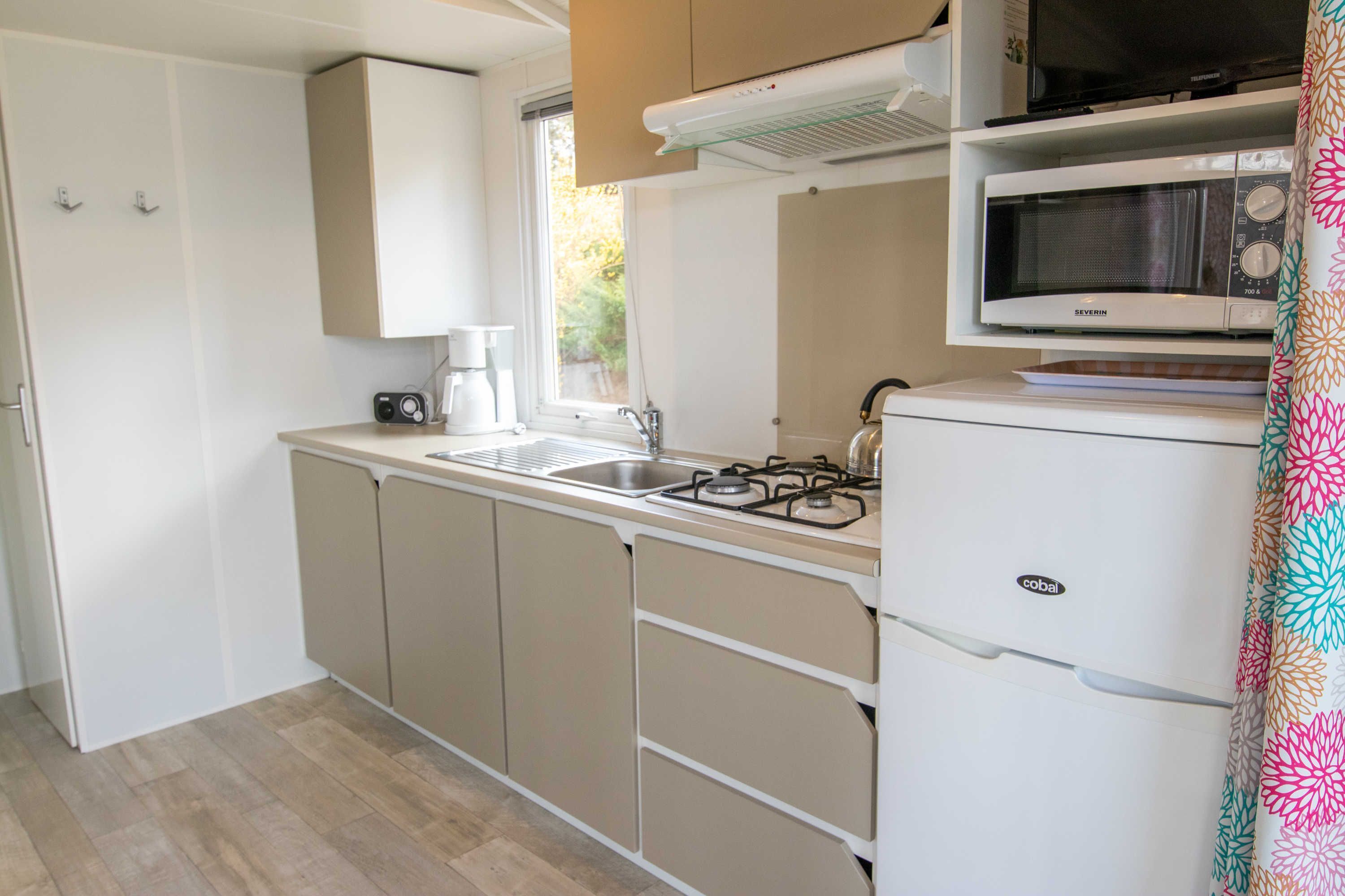 A compact kitchen with a gas stove, a microwave, a sink, and a coffee maker.