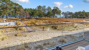 A beach view with a wooden deck, a bench, and a path leading to a dune area. - Gorgeous apartment in Binz with WiFi (Prora/Rügen)