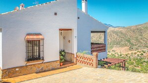 A white building with a stone foundation, a small window with metal bars, and a door with a light fixture. - Gorgeous home in Alora-El Chorro (Alora-El Chorro)
