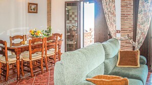 A living room with a green sofa, wooden dining table, chairs, and a patterned rug. - Gorgeous home in Alora-El Chorro (Alora-El Chorro)
