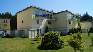 A two-story residential building with a balcony on the upper floor, a garage, and a well-maintained lawn.