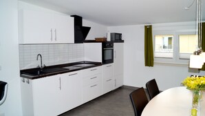 A modern kitchen with white cabinets, a black countertop, and a dining area with a table and chairs.