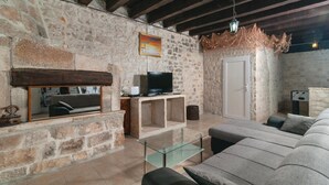 A stone-walled living room with a fireplace, a television, a sofa, and a door. - Amazing home in Pucisca (Pucisca)