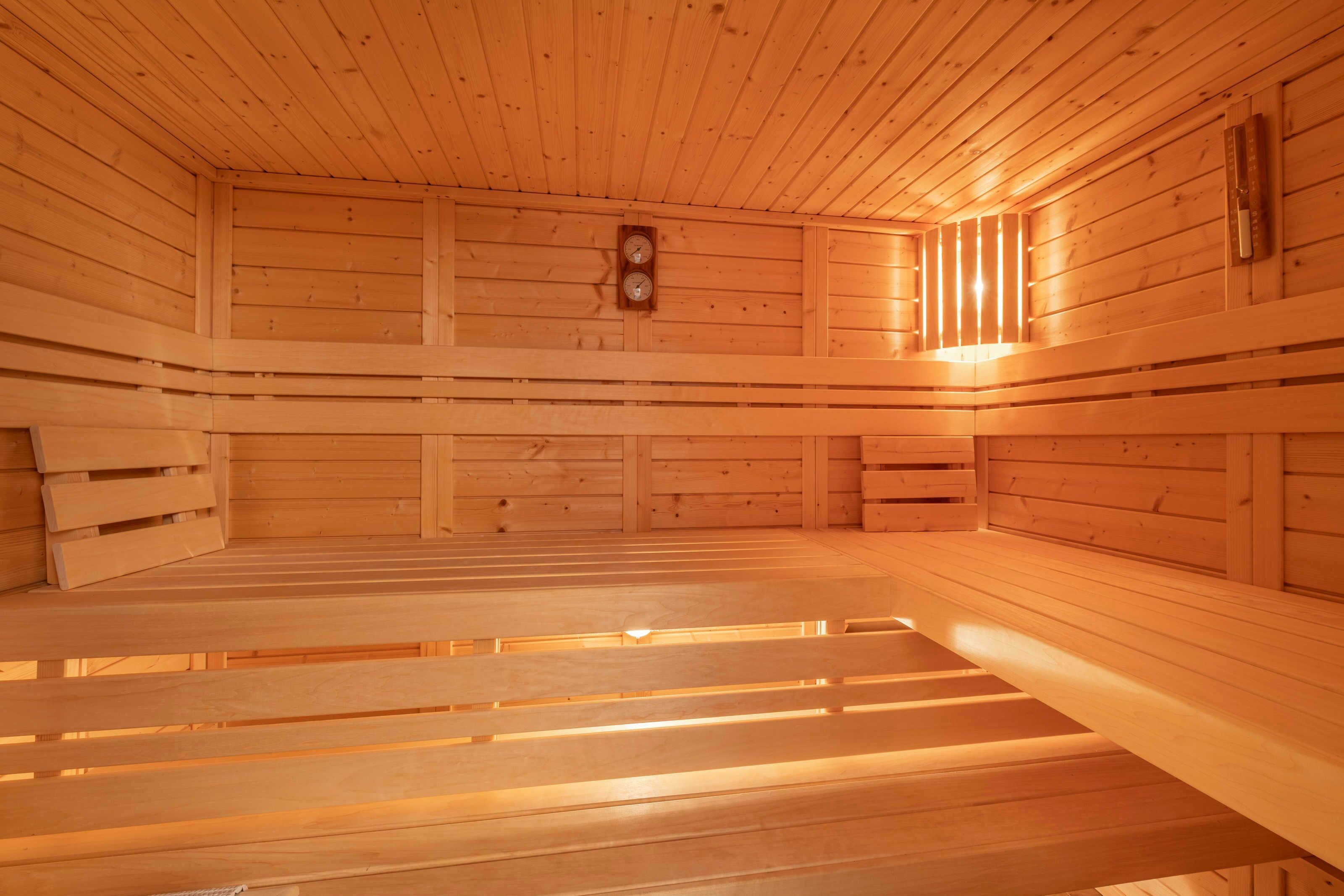 Eine Sauna mit hölzernen Bänken und einer Wanduhr.