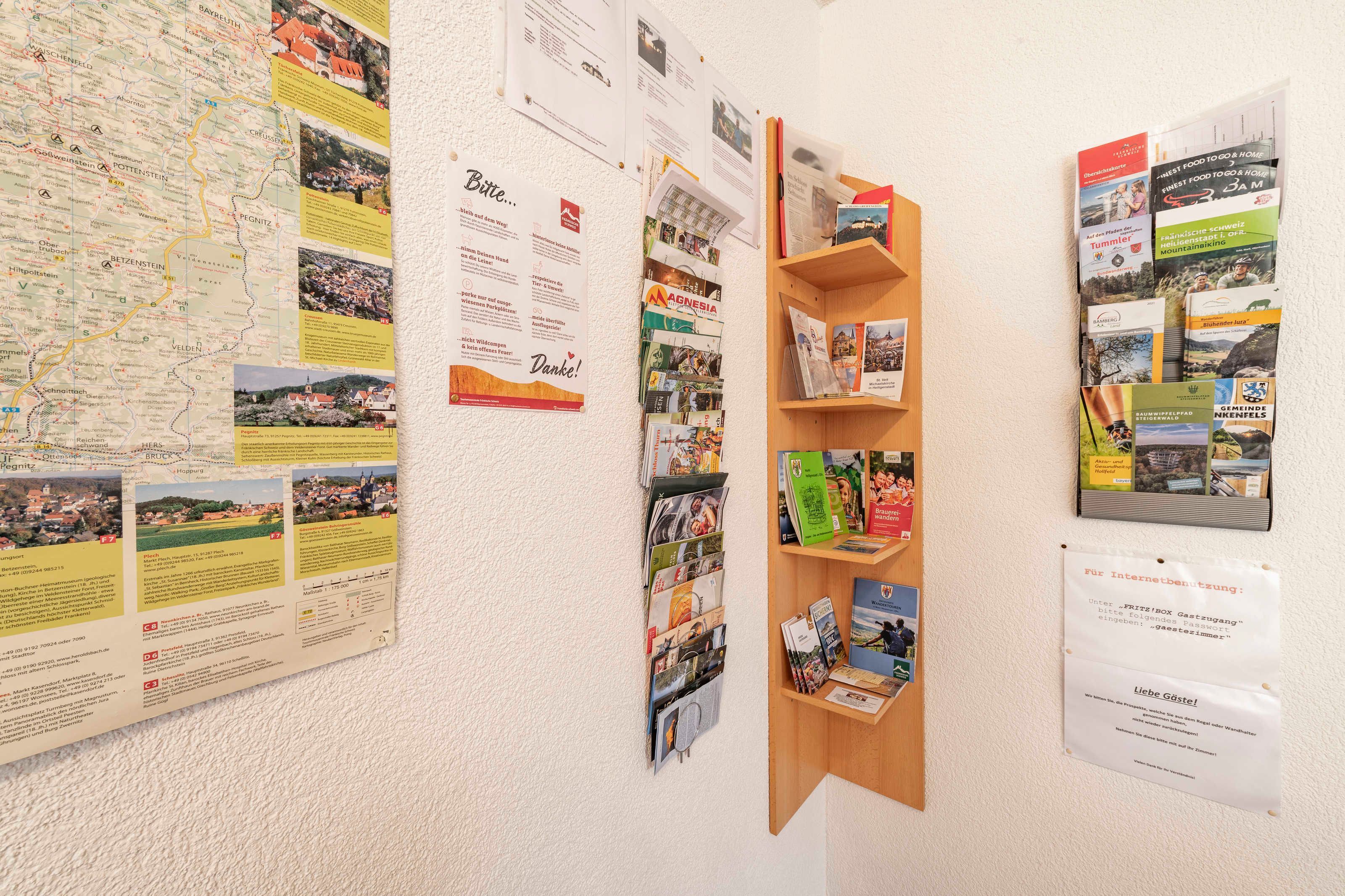 Una pared con un mapa, carteles informativos y un estante de madera con folletos.