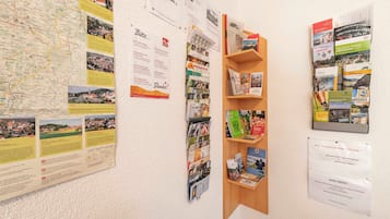 Una pared con un mapa, carteles informativos y un estante de madera con folletos.