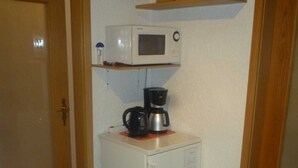 A compact kitchenette with a microwave, coffee maker, and a small refrigerator.